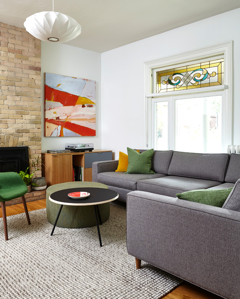 Inspiration för ett mellanstort minimalistiskt separat vardagsrum, med vita väggar, mellanmörkt trägolv, en standard öppen spis, en spiselkrans i tegelsten, en dold TV och brunt golv