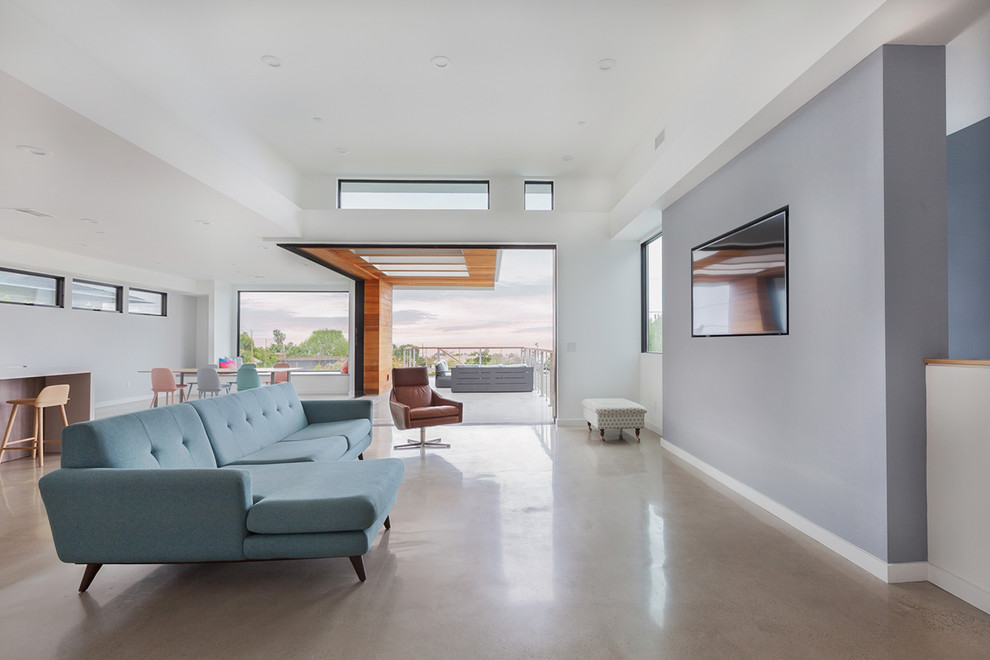 Immagine di un grande soggiorno contemporaneo aperto con pareti bianche, pavimento in cemento, nessun camino, TV a parete e pavimento grigio