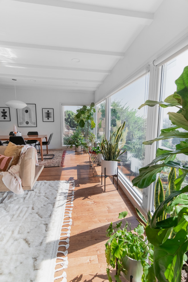 Mittelgroßes, Offenes Retro Wohnzimmer ohne Kamin mit weißer Wandfarbe, braunem Holzboden, TV-Wand und braunem Boden in Los Angeles