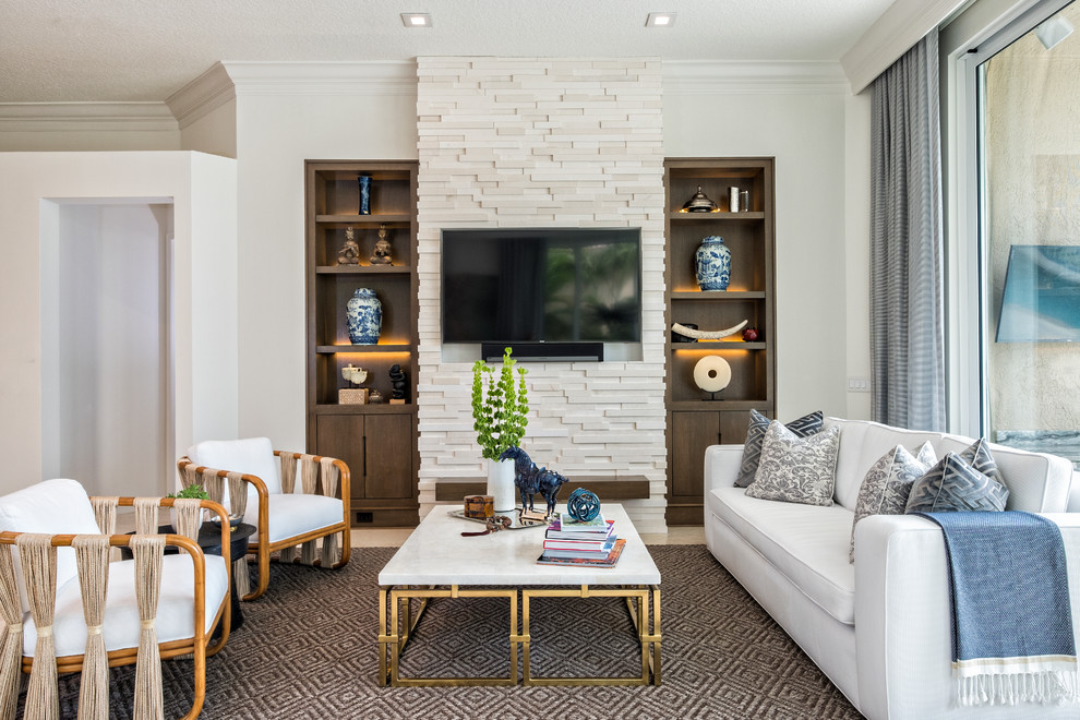 Стильный дизайн: большая открытая гостиная комната в современном стиле с белыми стенами, фасадом камина из камня, телевизором на стене и полом из известняка без камина - последний тренд