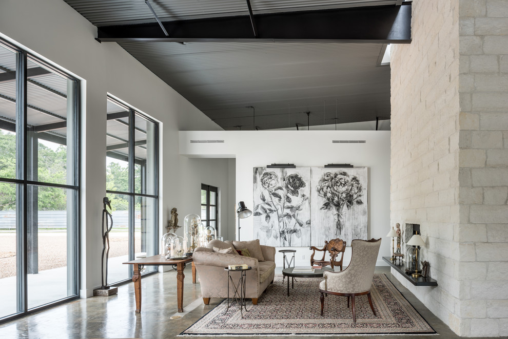 This is an example of a large industrial open plan living room in Houston with concrete flooring and a stone fireplace surround.