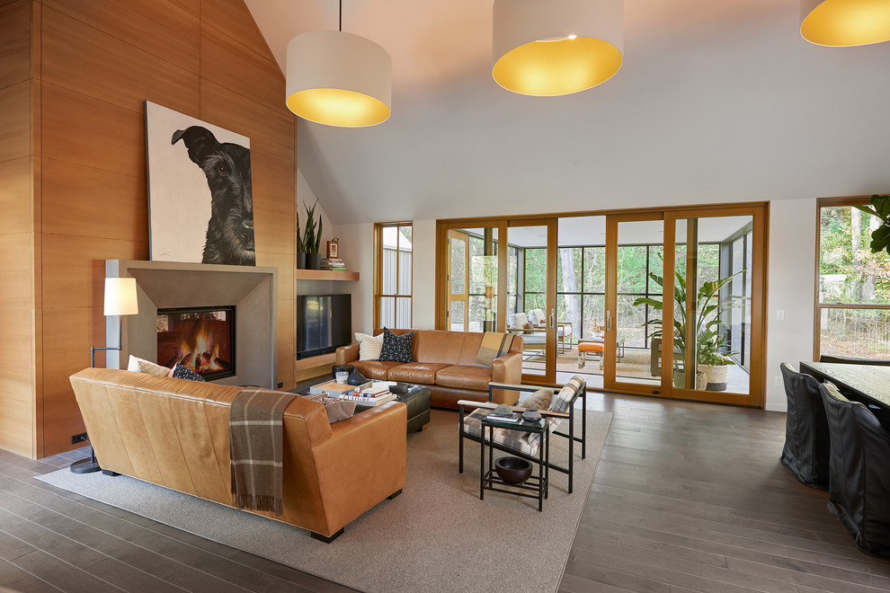Large contemporary open plan living room in Grand Rapids with white walls, a standard fireplace, a concrete fireplace surround, grey floors, medium hardwood flooring and a freestanding tv.
