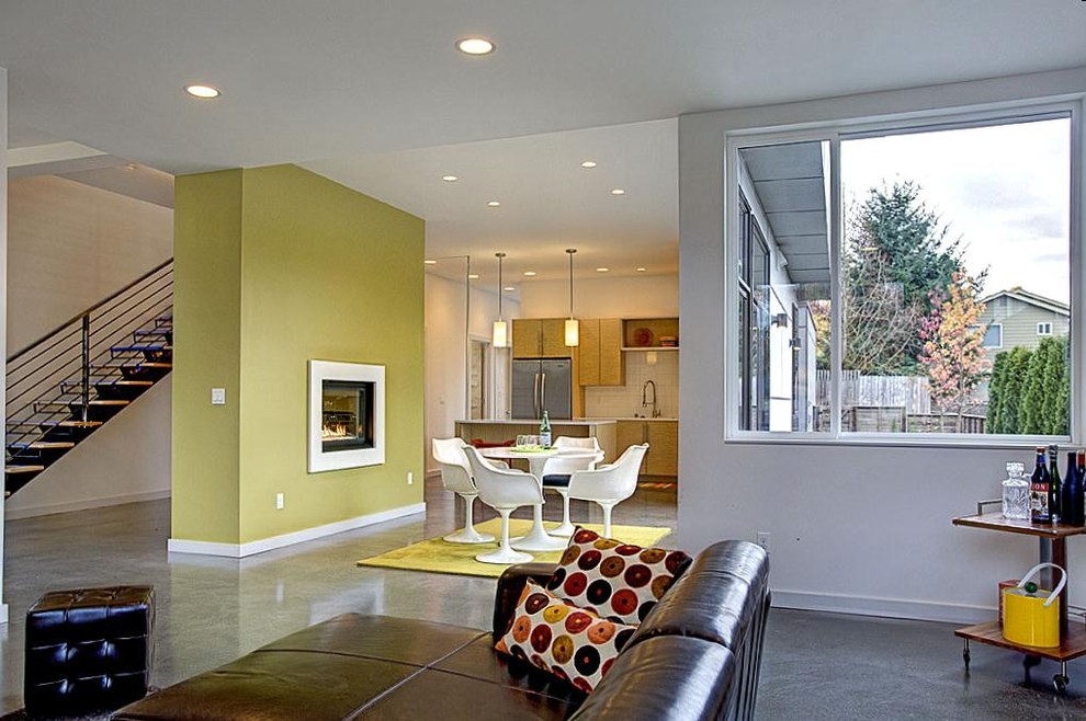 На фото: открытая гостиная комната среднего размера в современном стиле с разноцветными стенами, бетонным полом, стандартным камином и фасадом камина из штукатурки без телевизора