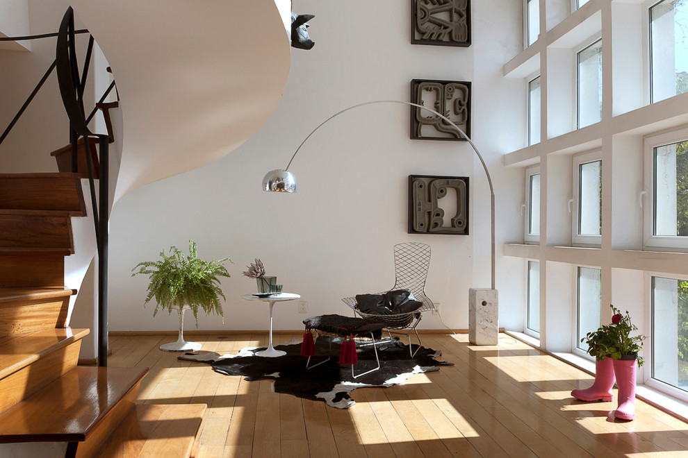 Cette image montre un salon design ouvert avec une salle de réception, un mur blanc, un sol en bois brun, aucune cheminée, aucun téléviseur et un escalier.