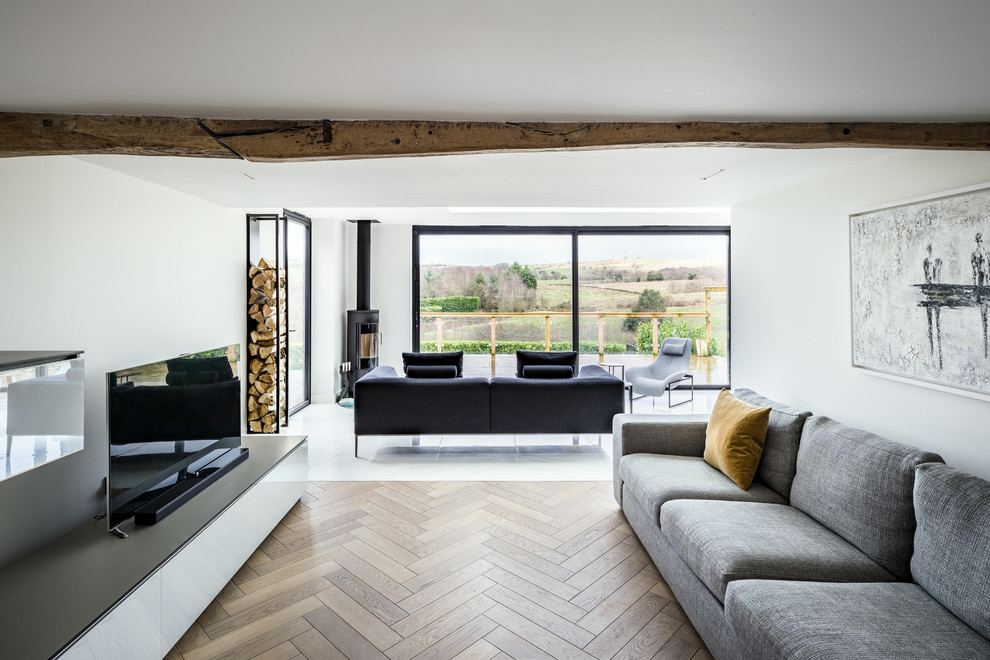 Inspiration pour un salon design de taille moyenne avec un mur blanc, un sol en bois brun, un poêle à bois, un téléviseur indépendant, un sol beige et canapé noir.