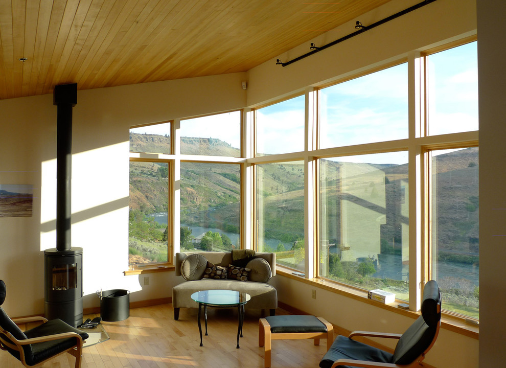 Foto di un soggiorno minimal aperto con sala formale, pareti gialle, parquet chiaro, stufa a legna, cornice del camino in metallo e nessuna TV