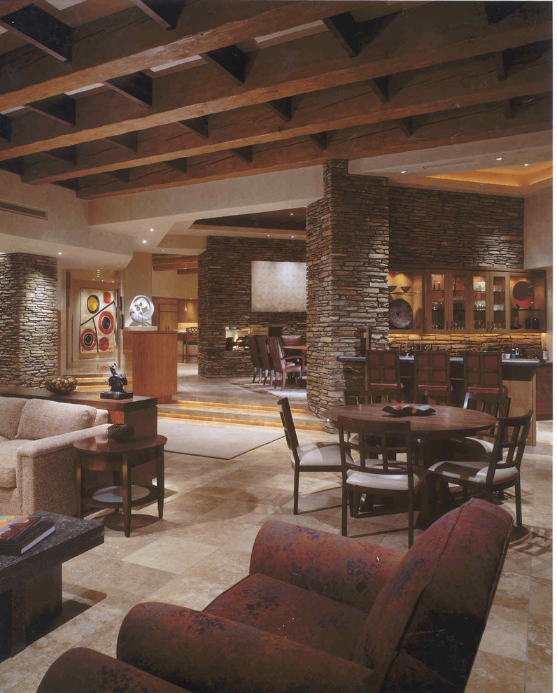 Aménagement d'un très grand salon sud-ouest américain ouvert avec un bar de salon, un mur beige, un sol en travertin, une cheminée standard, un manteau de cheminée en pierre et un téléviseur encastré.