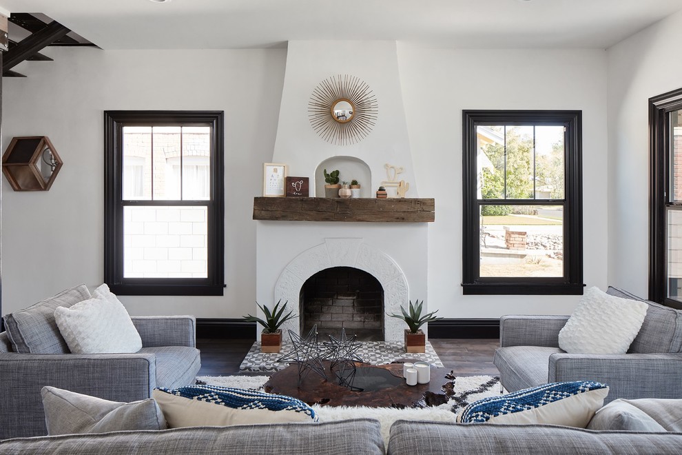 Cette photo montre un salon éclectique avec un mur blanc, parquet foncé, une cheminée standard, un manteau de cheminée en carrelage et un sol marron.