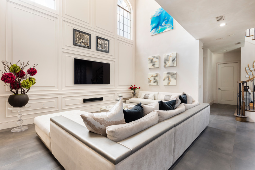 Источник вдохновения для домашнего уюта: большая открытая гостиная комната в современном стиле с белыми стенами, полом из керамогранита, телевизором на стене и серым полом без камина