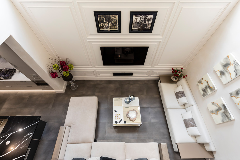 Imagen de salón para visitas abierto actual grande con paredes blancas, suelo de baldosas de porcelana, televisor colgado en la pared y suelo gris