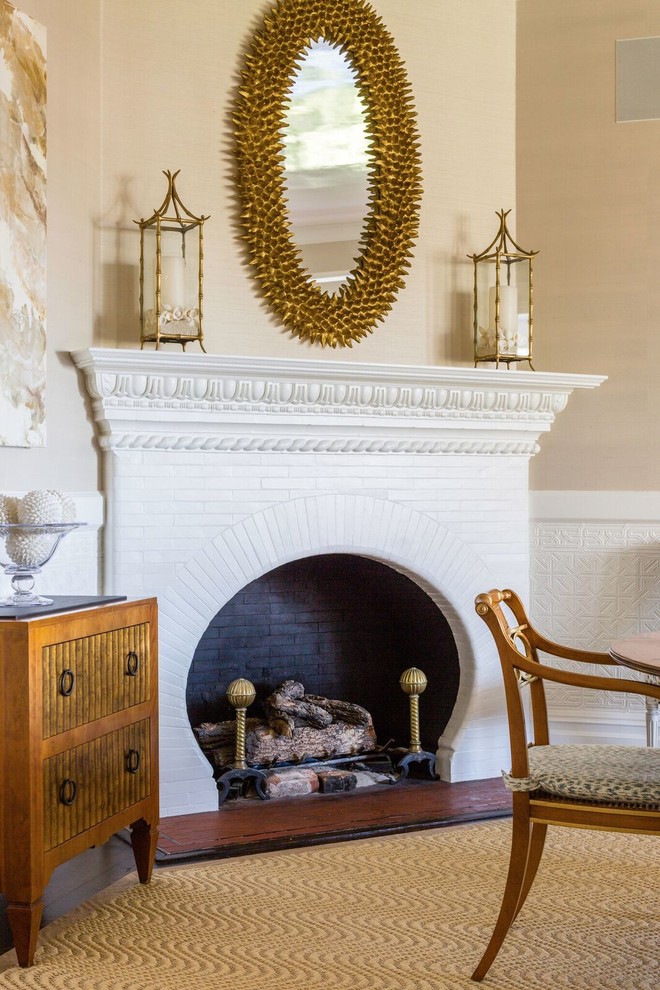 Aménagement d'un salon classique avec un mur beige, parquet foncé, une cheminée d'angle, un manteau de cheminée en brique et un sol marron.