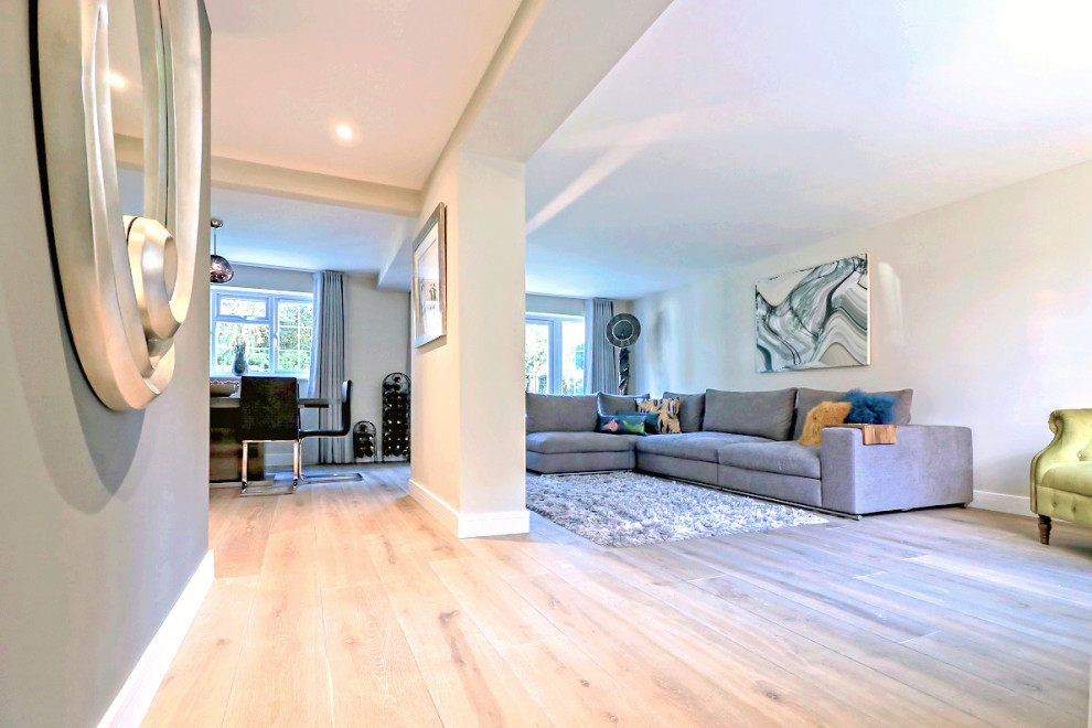 Cette image montre un salon minimaliste de taille moyenne et ouvert avec un sol en bois brun, un mur beige et un sol beige.