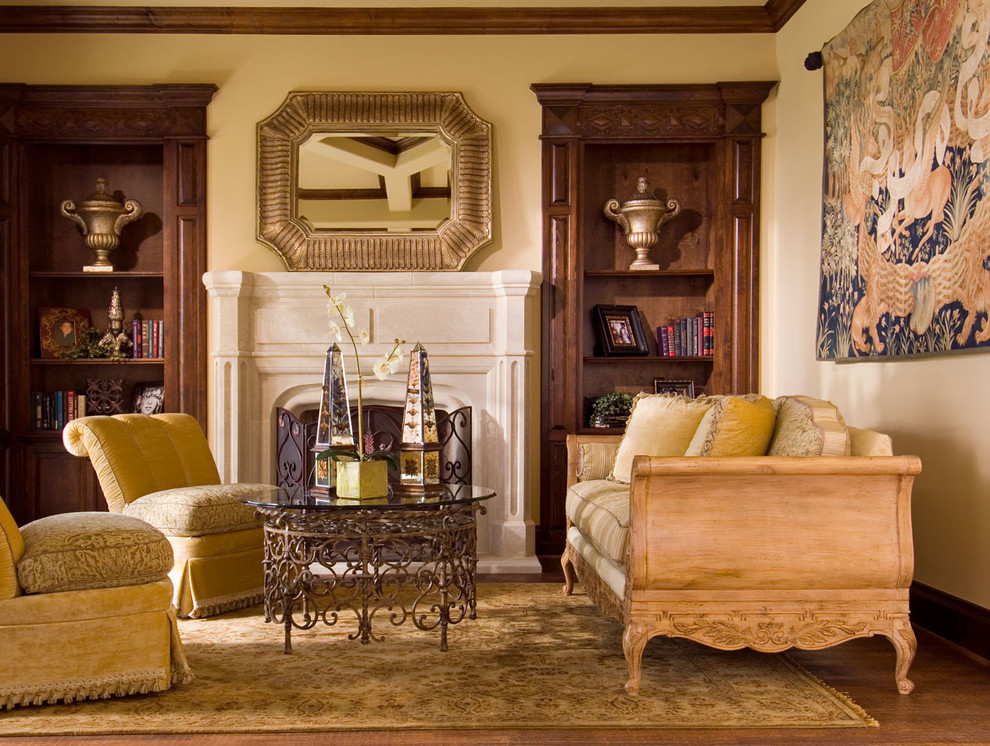 Ejemplo de biblioteca en casa abierta tradicional grande con paredes beige, suelo de madera en tonos medios, todas las chimeneas, marco de chimenea de piedra y suelo marrón