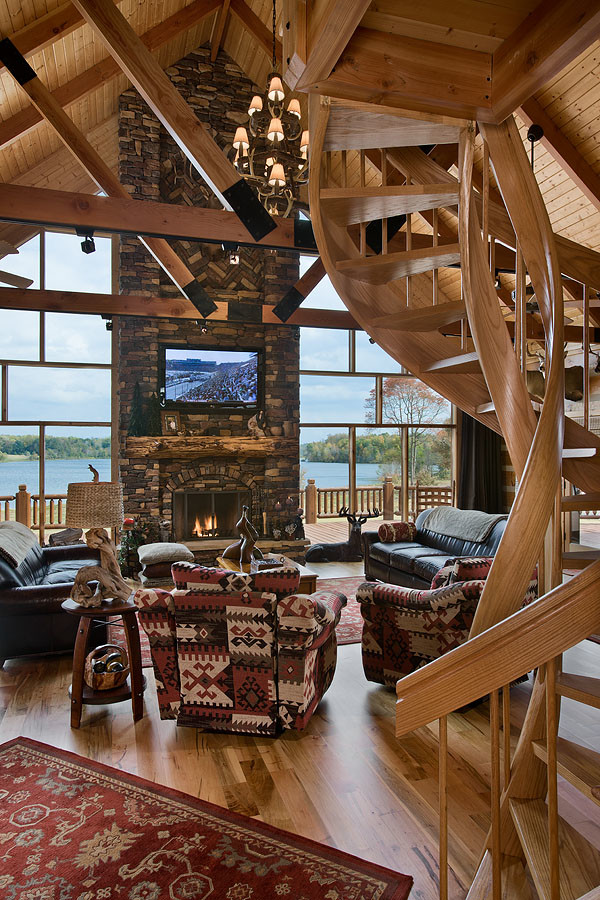 This is an example of a large rustic formal open plan living room in Other with light hardwood flooring, a standard fireplace, a stone fireplace surround, a wall mounted tv and brown walls.