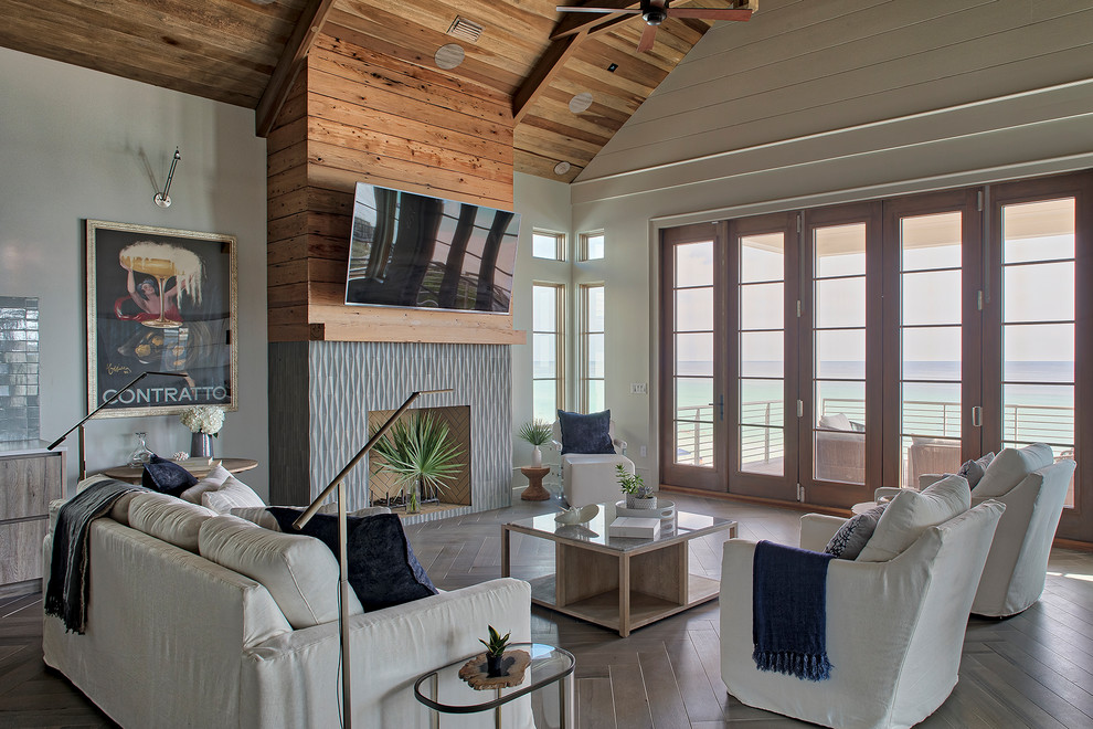 Offenes Maritimes Wohnzimmer mit beiger Wandfarbe, Kamin, gefliester Kaminumrandung, TV-Wand und braunem Boden in Sonstige