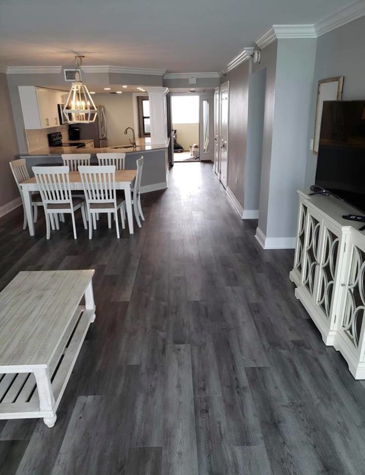 Example of a mid-sized beach style formal and open concept vinyl floor and gray floor living room design in Miami with gray walls, no fireplace and a tv stand