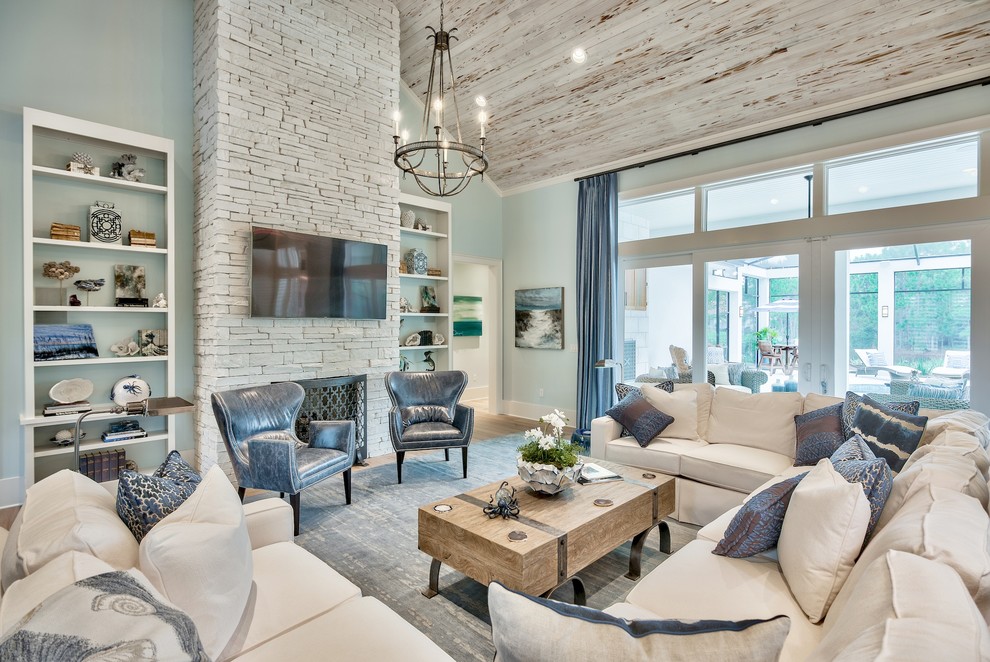 Источник вдохновения для домашнего уюта: гостиная комната в морском стиле с синими стенами, паркетным полом среднего тона, стандартным камином, фасадом камина из камня, телевизором на стене, коричневым полом и синими шторами