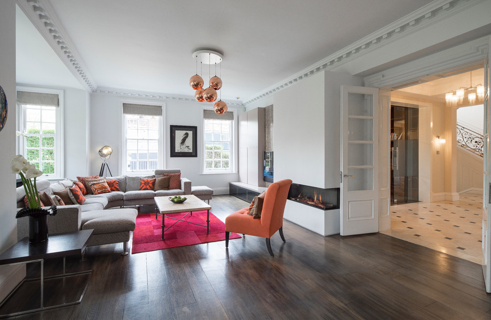 Стильный дизайн: парадная, изолированная гостиная комната в современном стиле с белыми стенами, темным паркетным полом, горизонтальным камином и коричневым полом - последний тренд