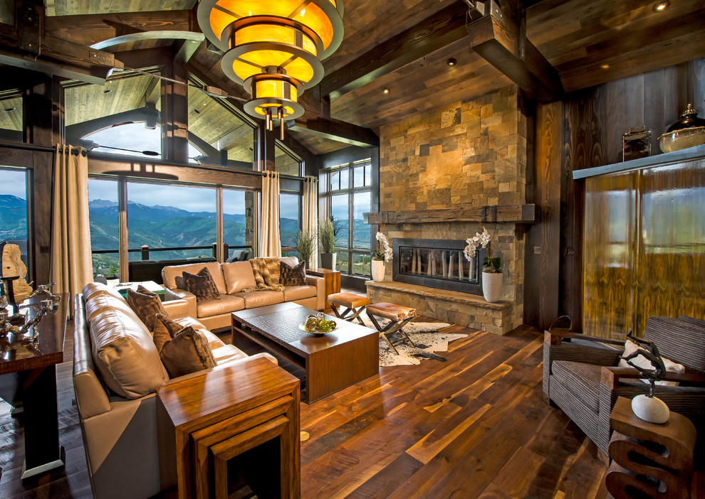 Inspiration for a large rustic open plan living room in Other with dark hardwood flooring, a standard fireplace, a stone fireplace surround, a concealed tv and brown floors.