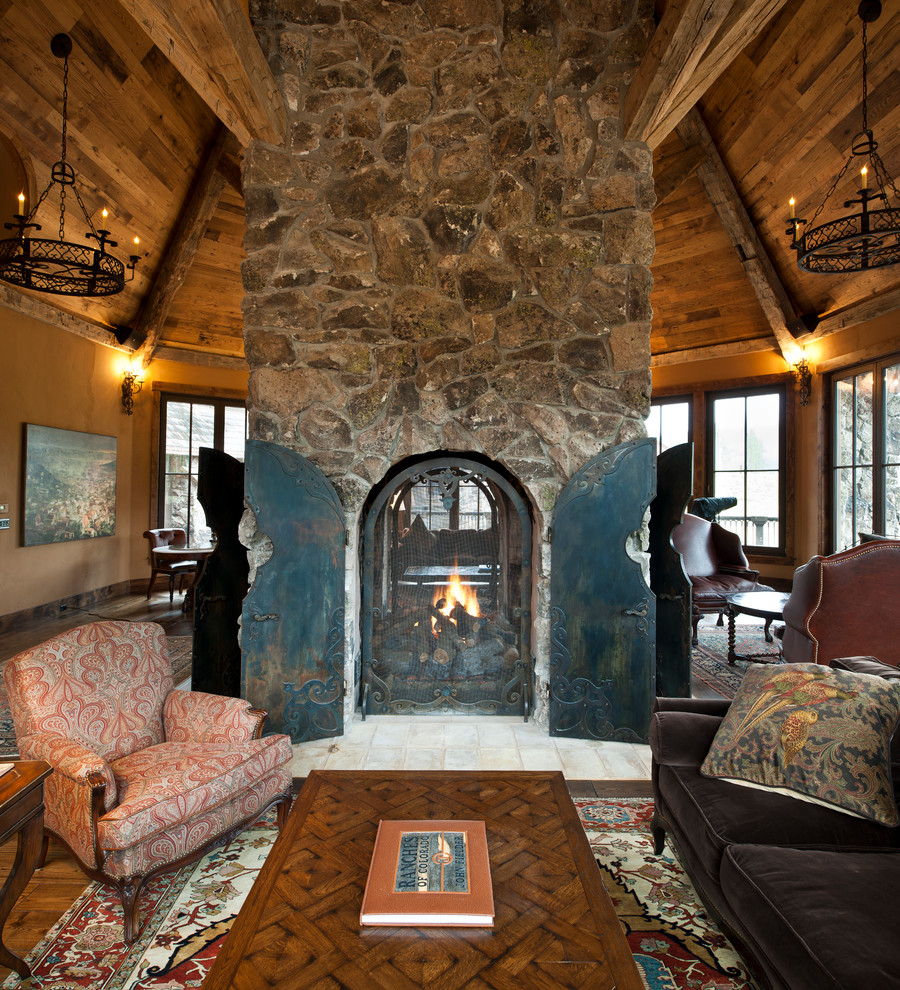 デンバーにあるラスティックスタイルのおしゃれなリビング (ベージュの壁、両方向型暖炉、石材の暖炉まわり) の写真