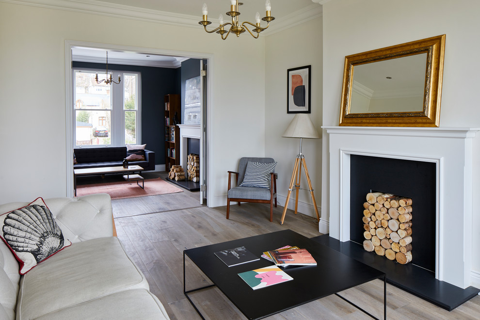 Mittelgroßes, Abgetrenntes Modernes Wohnzimmer mit weißer Wandfarbe, hellem Holzboden, Kamin, Kaminumrandung aus Metall, freistehendem TV und braunem Boden in London