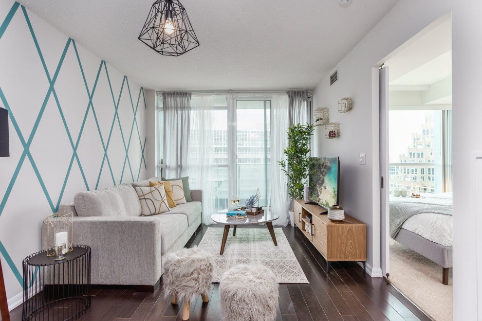 Offenes Modernes Wohnzimmer ohne Kamin mit weißer Wandfarbe, dunklem Holzboden, freistehendem TV und braunem Boden in Toronto