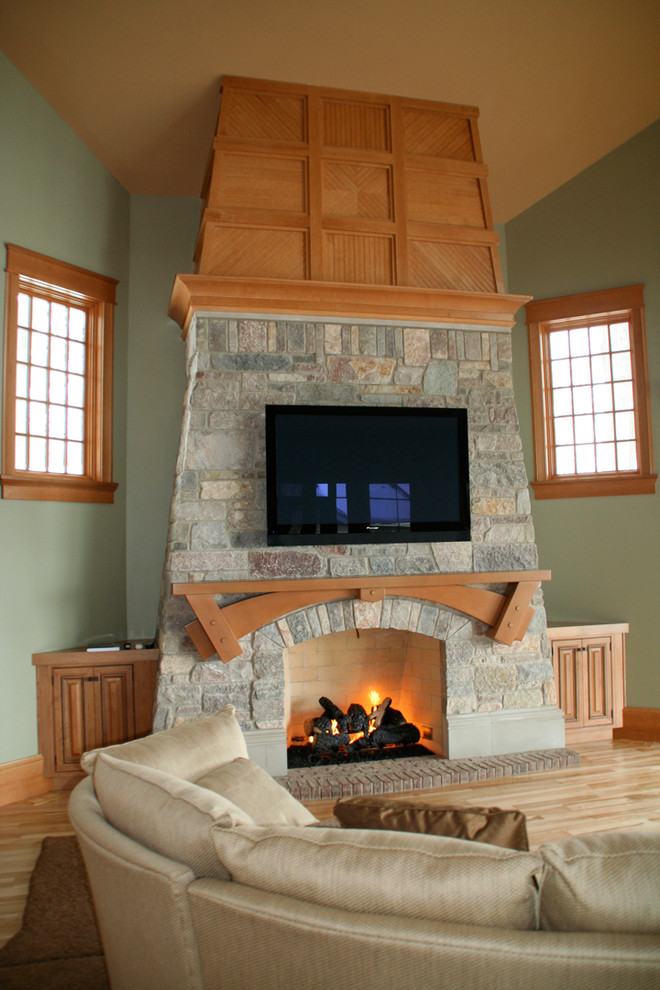 Imagen de salón abierto de estilo americano de tamaño medio con paredes verdes, suelo de madera clara, todas las chimeneas, marco de chimenea de piedra y televisor colgado en la pared
