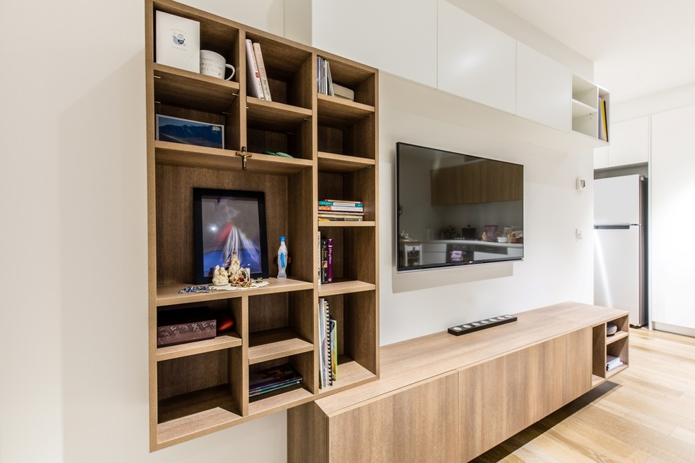 Modern inredning av ett mellanstort vardagsrum, med en väggmonterad TV, vita väggar och mellanmörkt trägolv