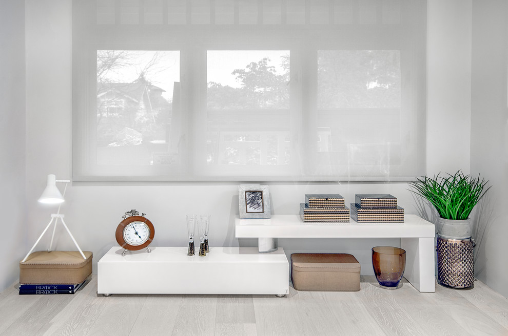 Esempio di un soggiorno design chiuso con pareti bianche, parquet chiaro, camino classico, TV nascosta e pavimento beige