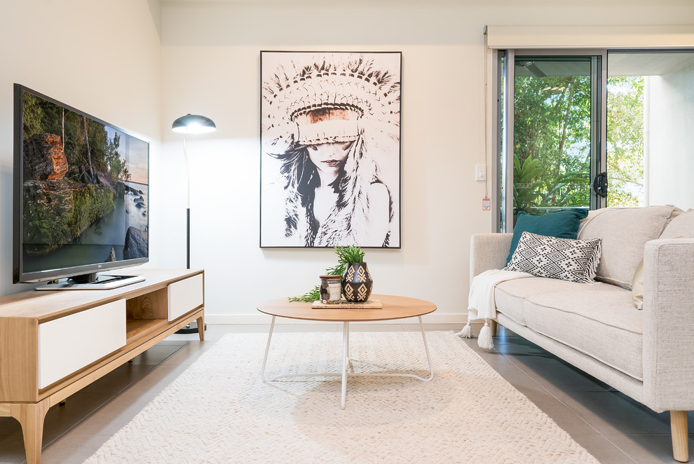 Foto på ett minimalistiskt vardagsrum, med vita väggar, en fristående TV och grått golv