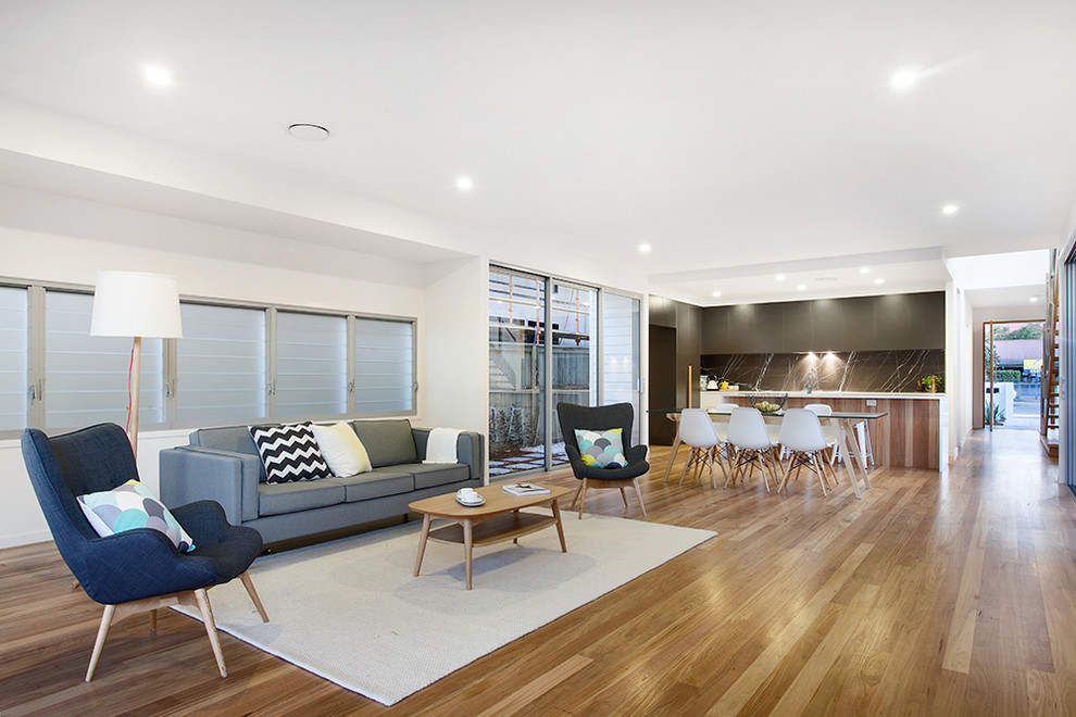This is an example of a scandi open plan living room in Brisbane with white walls and medium hardwood flooring.