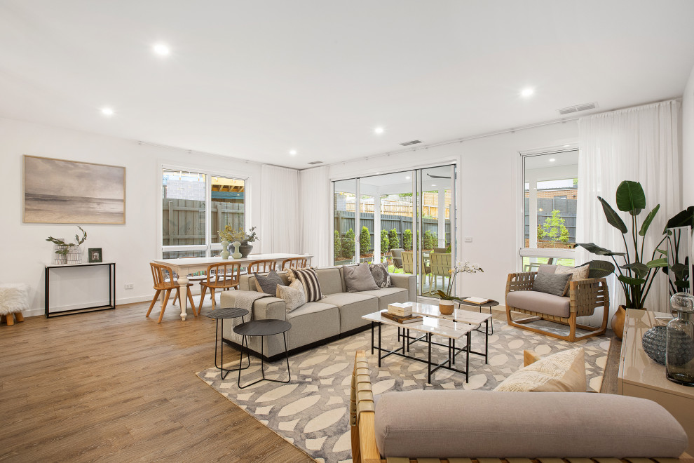 Mittelgroßes, Offenes Klassisches Wohnzimmer ohne Kamin mit weißer Wandfarbe, Laminat, freistehendem TV und braunem Boden in Melbourne