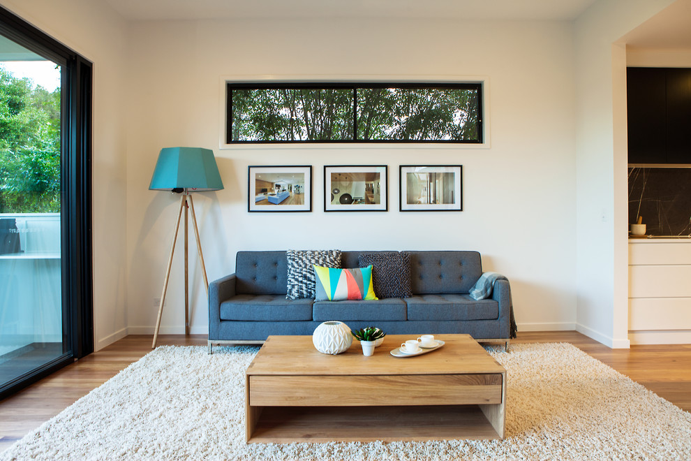 Offenes Nordisches Wohnzimmer mit weißer Wandfarbe, braunem Holzboden und freistehendem TV in Brisbane