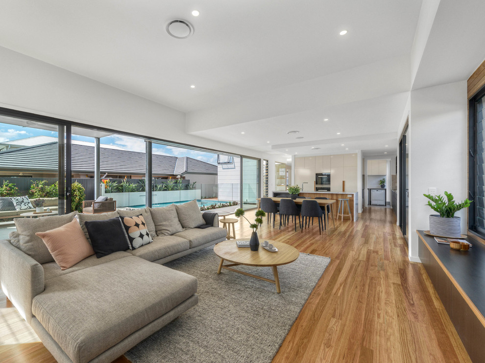 Example of a trendy open concept medium tone wood floor living room design in Brisbane with white walls and a wall-mounted tv