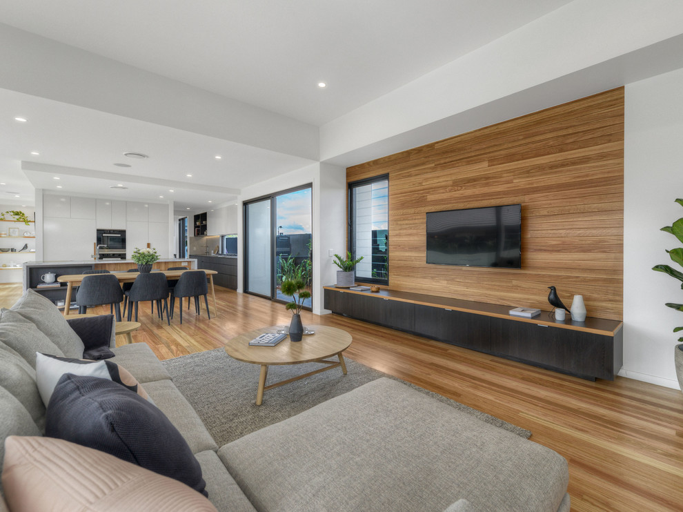 Contemporary open plan living room in Brisbane with white walls, medium hardwood flooring and a wall mounted tv.