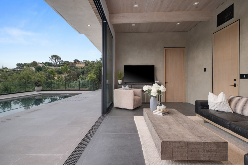 Modelo de salón abierto moderno de tamaño medio con paredes beige, televisor independiente, suelo gris y madera