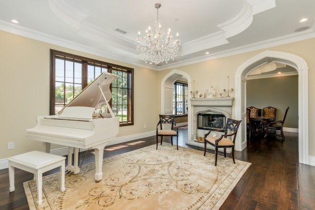Medium sized victorian enclosed living room in San Diego with a music area, beige walls, medium hardwood flooring, a standard fireplace, a concrete fireplace surround and no tv.