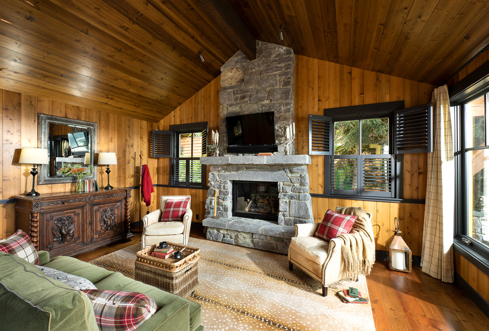Example of a mountain style medium tone wood floor and brown floor living room design in Other with brown walls, a standard fireplace and a stone fireplace