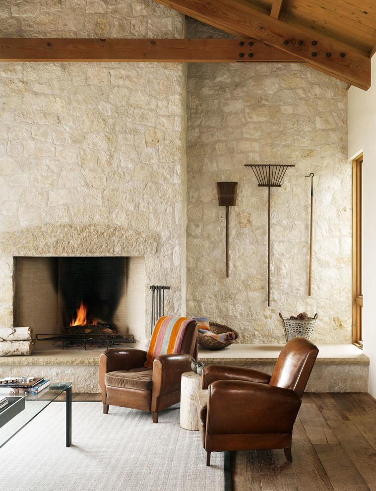 Diseño de salón campestre sin televisor con paredes beige, suelo de madera oscura, todas las chimeneas, marco de chimenea de piedra, suelo marrón y piedra