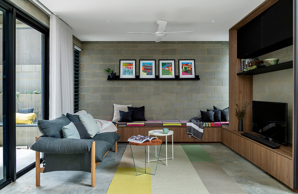 Foto de salón abierto moderno con paredes grises, suelo de cemento, televisor independiente, suelo gris y ladrillo
