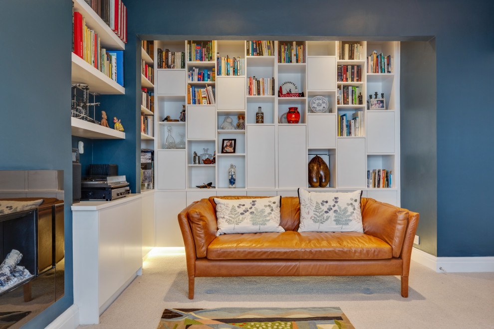 Immagine di un soggiorno minimal di medie dimensioni e chiuso con libreria, pareti blu, moquette, camino sospeso, TV a parete e pavimento grigio