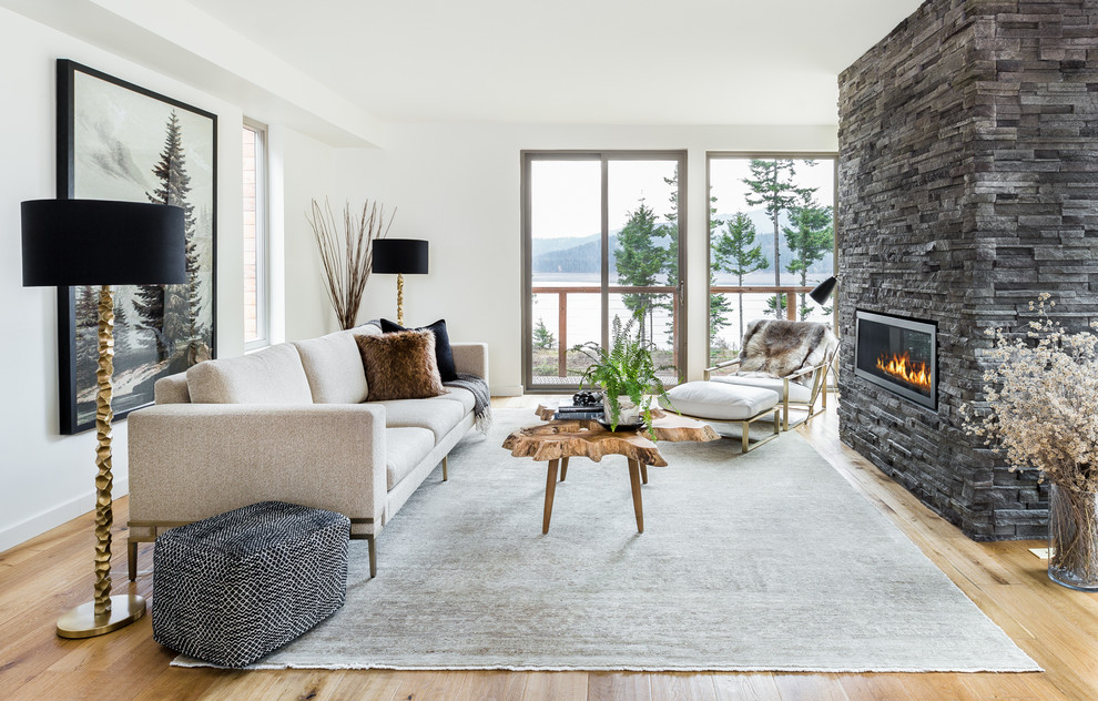 Offenes Modernes Wohnzimmer mit weißer Wandfarbe, braunem Holzboden, Gaskamin und Kaminumrandung aus Stein in Seattle
