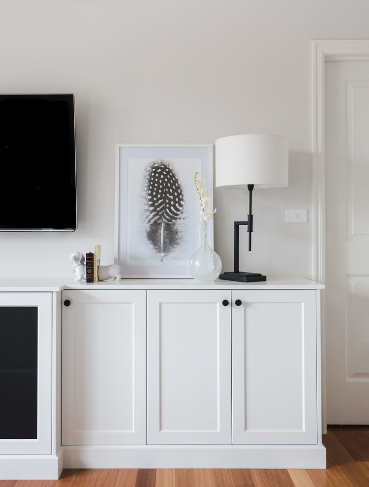 Imagen de salón abierto clásico renovado grande con paredes blancas, suelo de madera clara y televisor colgado en la pared