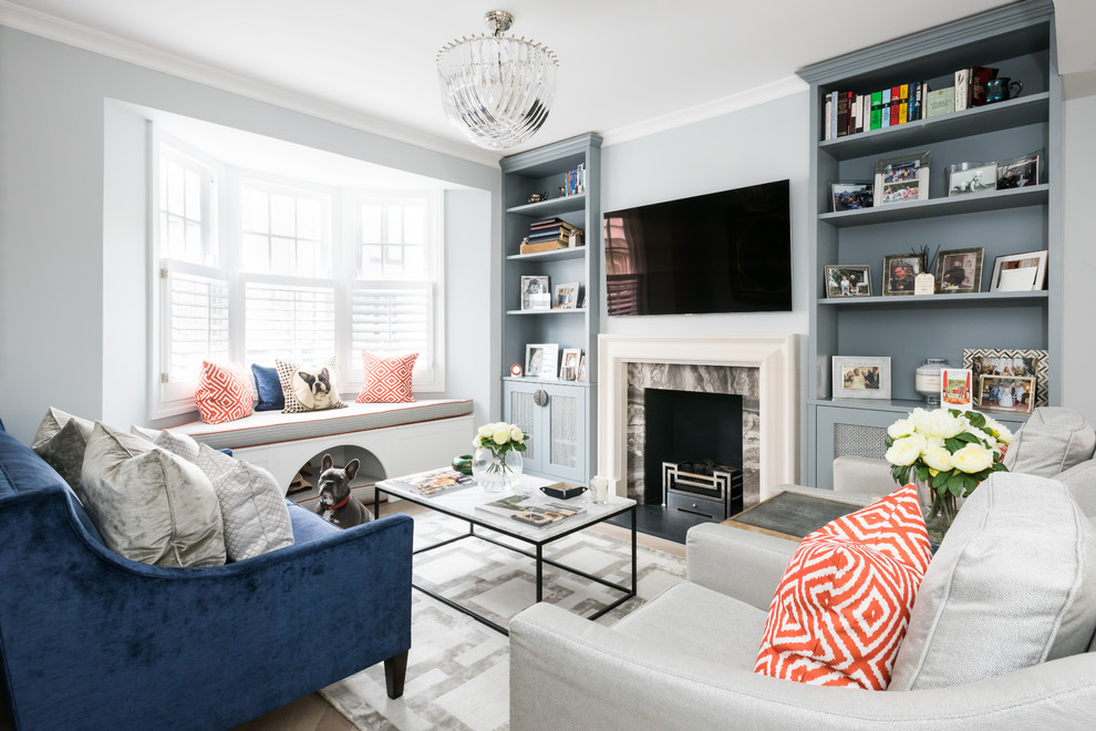 Стильный дизайн: гостиная комната в стиле неоклассика (современная классика) с синими стенами, стандартным камином, фасадом камина из камня, телевизором на стене и эркером - последний тренд