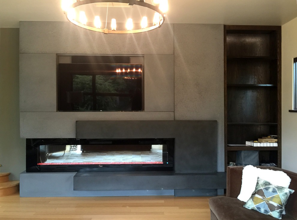 Photo of a contemporary living room in Denver with a hanging fireplace, a concrete fireplace surround and a wall mounted tv.