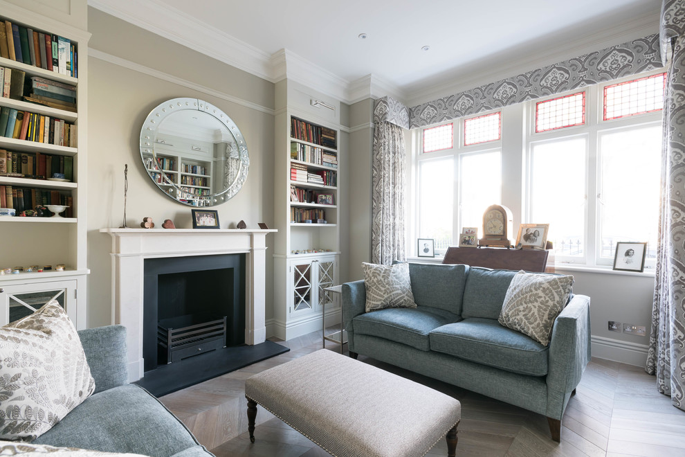 This is an example of a large traditional formal enclosed living room in London with beige walls, light hardwood flooring, a standard fireplace and no tv.