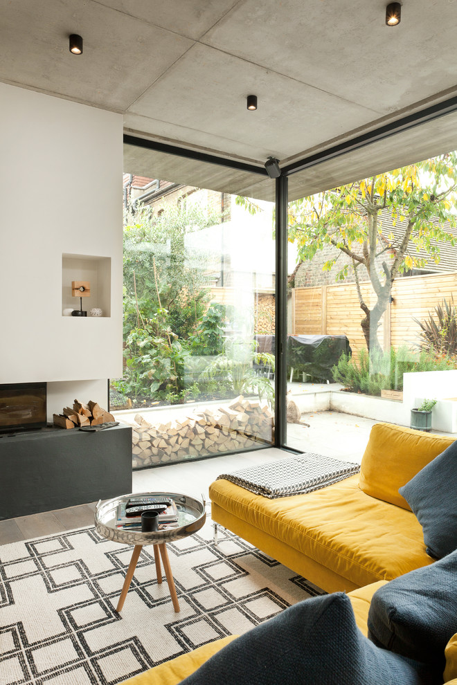 Photo of a medium sized contemporary enclosed living room in London with a reading nook, grey walls, light hardwood flooring, a wood burning stove, a plastered fireplace surround and a wall mounted tv.