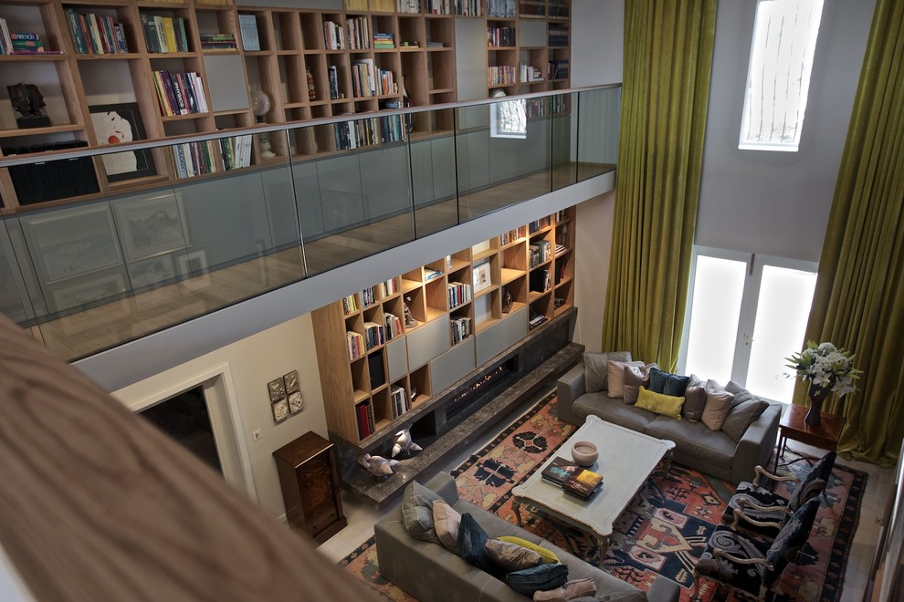 Foto de biblioteca en casa tipo loft actual grande sin televisor con paredes grises, suelo de mármol, chimenea lineal y marco de chimenea de piedra