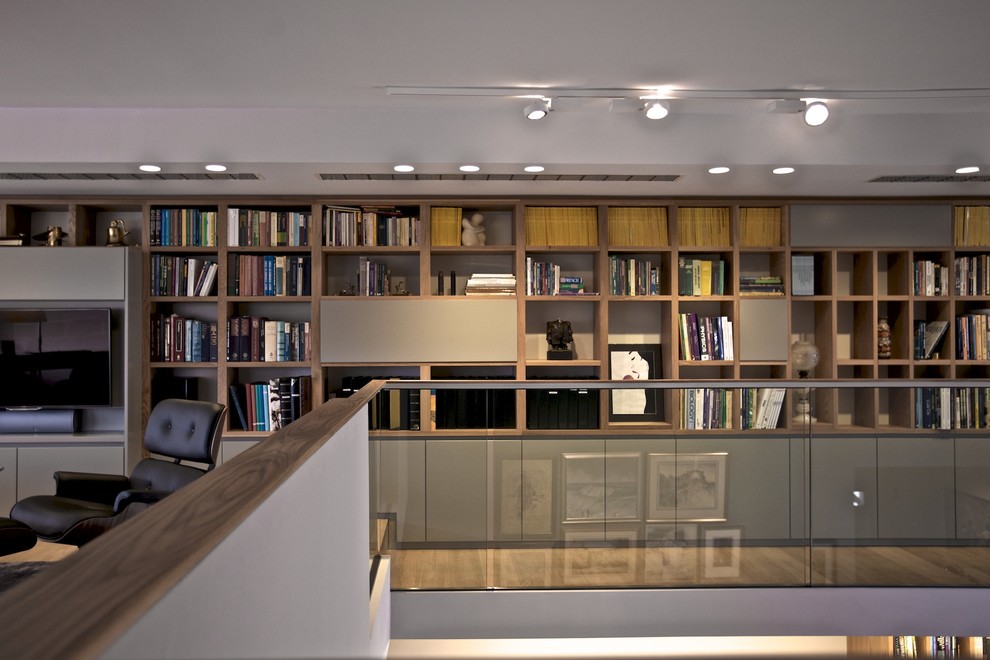 Modern inredning av ett stort loftrum, med ett bibliotek, grå väggar, marmorgolv, en bred öppen spis och en spiselkrans i sten