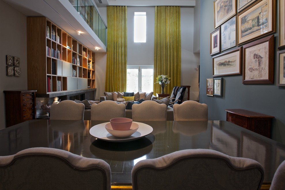 На фото: большая двухуровневая гостиная комната в современном стиле с с книжными шкафами и полками, серыми стенами, мраморным полом, горизонтальным камином и фасадом камина из камня без телевизора с